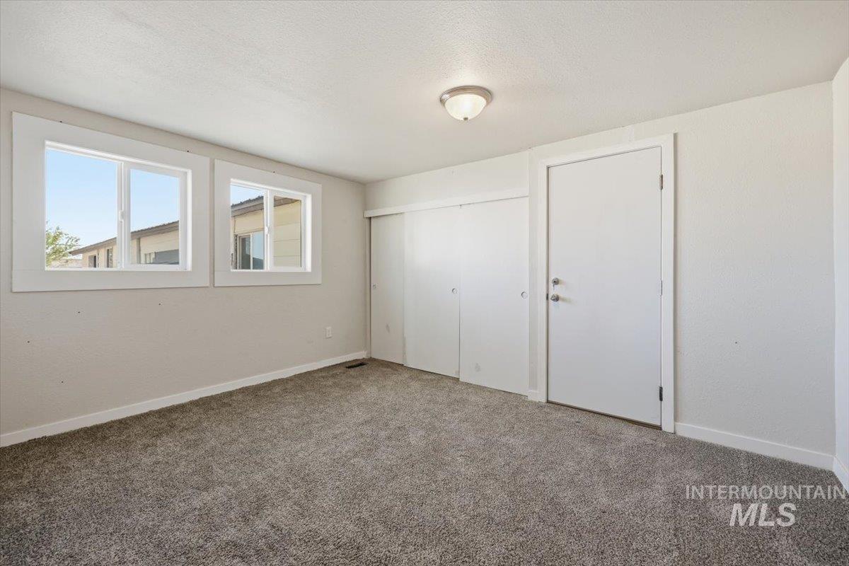 956 Southeast Hamilton Road Mountain Home, ID 83647 - Photo 25 of 34 Carpeted room featuring two large windows with white trim, a flush-mount ceiling light, and two white sliding closet doors