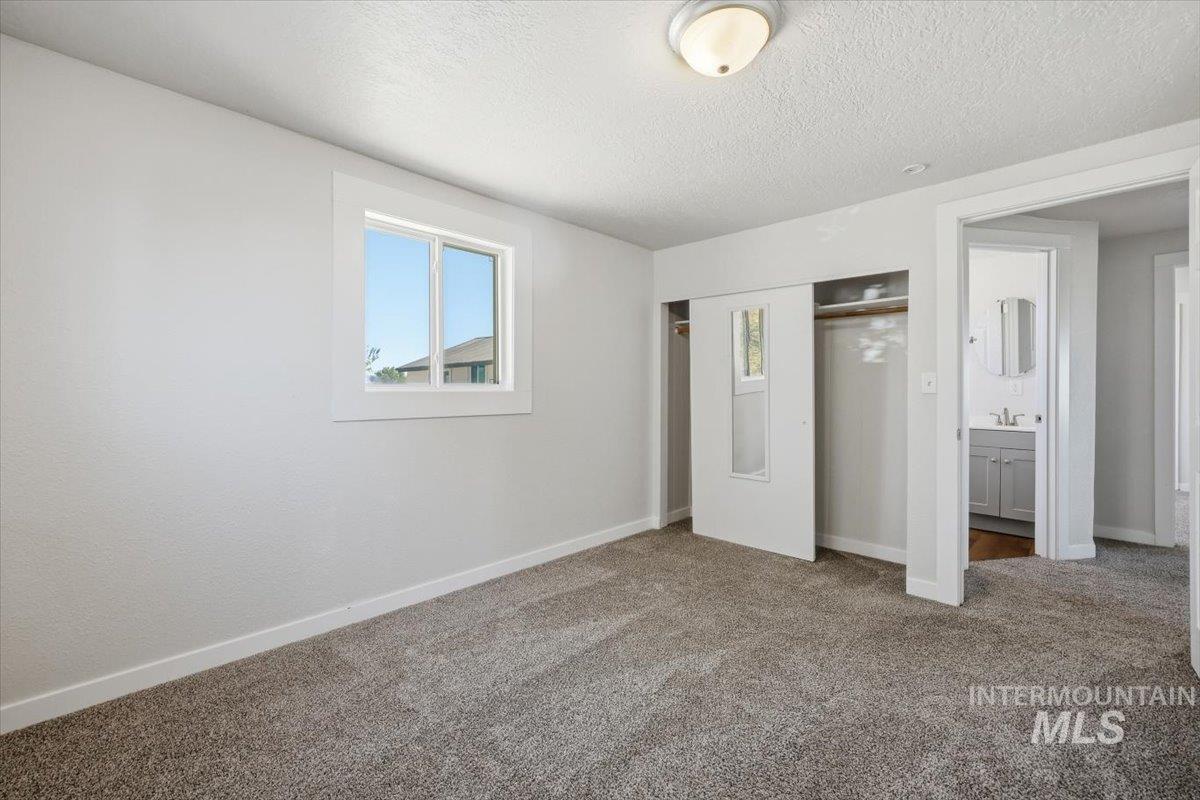 956 Southeast Hamilton Road Mountain Home, ID 83647 - Photo 28 of 34 Neutral carpeted room featuring a single window with white trim, a flush-mount ceiling light, and sliding closet doors with mirrored panels
