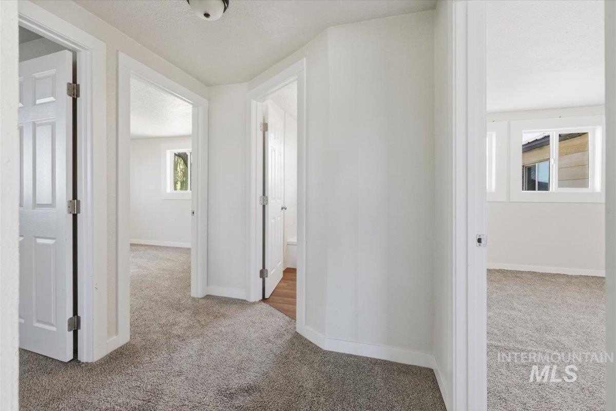 956 Southeast Hamilton Road Mountain Home, ID 83647 - Photo 32 of 34 Interior hallway with neutral carpeting, white walls, and multiple paneled doors providing access to various rooms