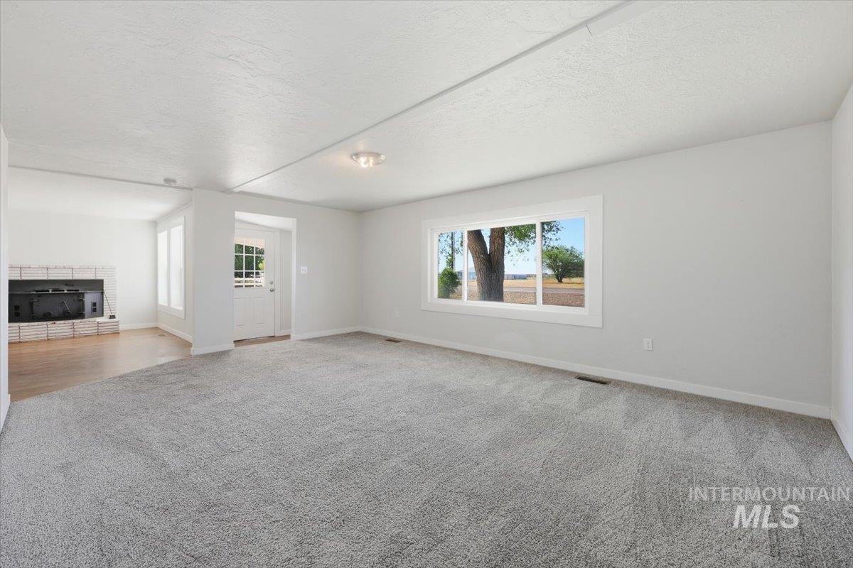 956 Southeast Hamilton Road Mountain Home, ID 83647 - Photo 33 of 34 Living area featuring neutral-toned carpet, a large window, white walls, and a ceiling light fixture