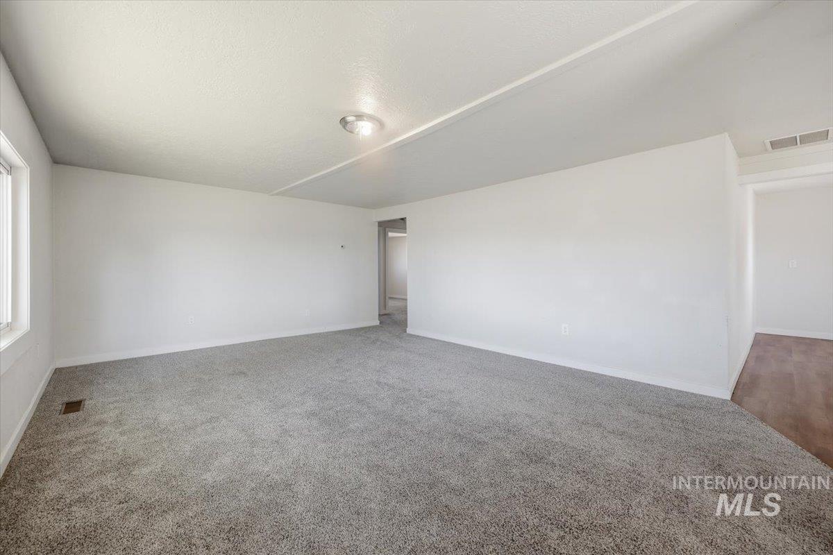 956 Southeast Hamilton Road Mountain Home, ID 83647 - Photo 10 of 34 Spacious room featuring neutral carpeting, white walls, a flush-mount ceiling light, and natural light from a window