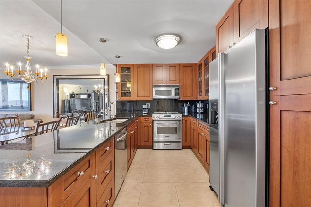 a large kitchen with stainless steel appliances granite countertop a refrigerator a sink a stove and island