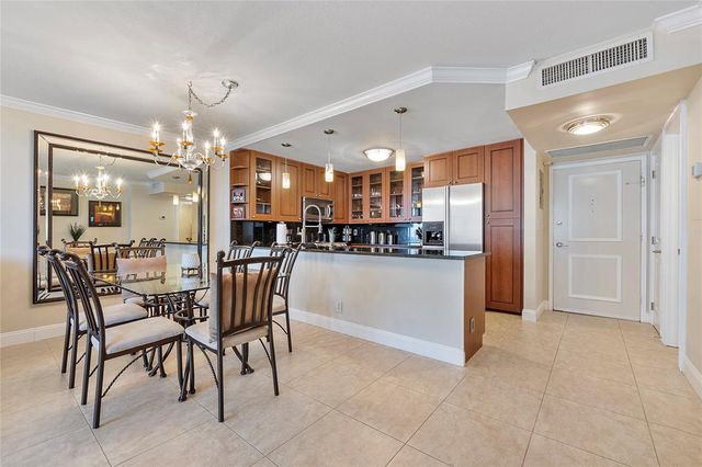 a kitchen with kitchen island a dining table chairs stainless steel appliances and cabinets