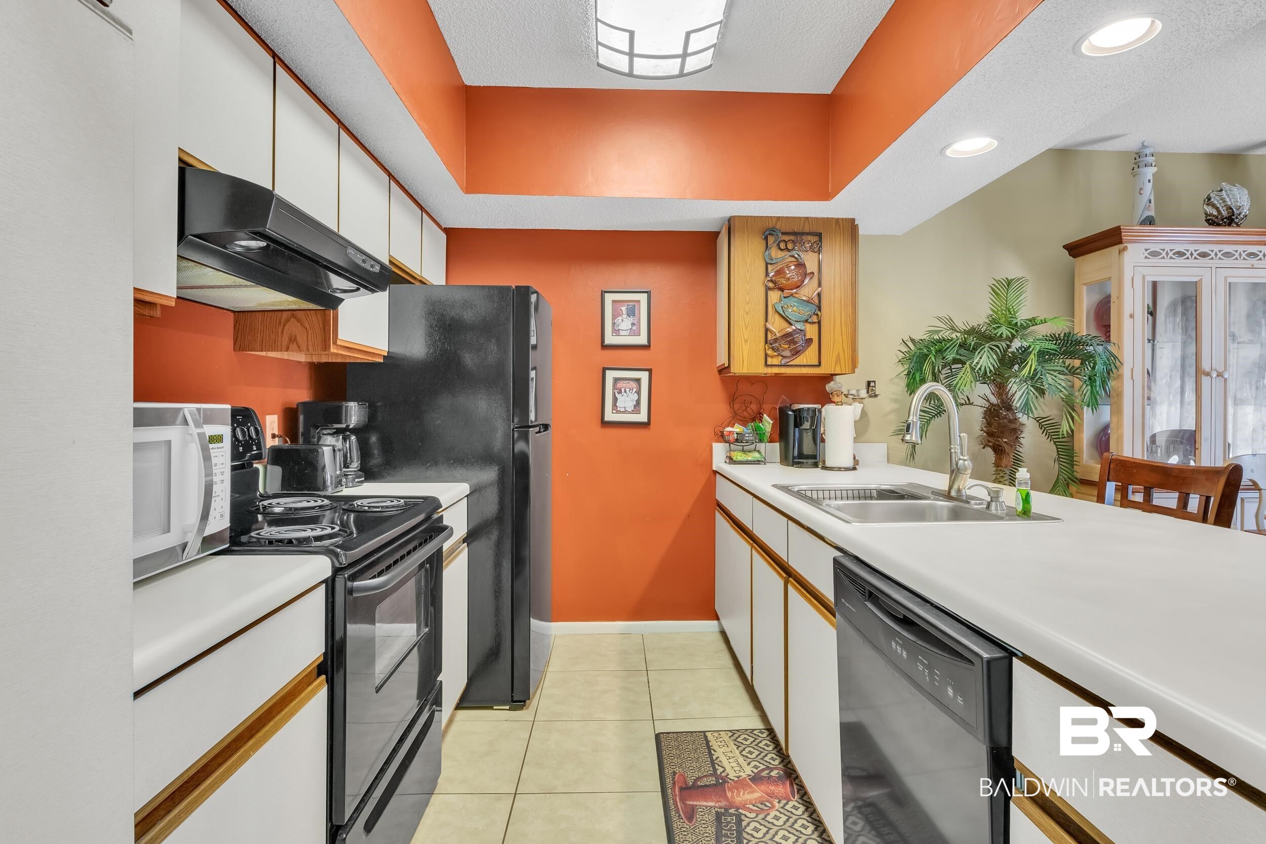 3256 Loop Road, Unit 2 Orange Beach, AL 36561 - Photo 16 of 25 Galley kitchen featuring white cabinetry with wood-finish accents, black appliances, a double basin sink, and tile flooring