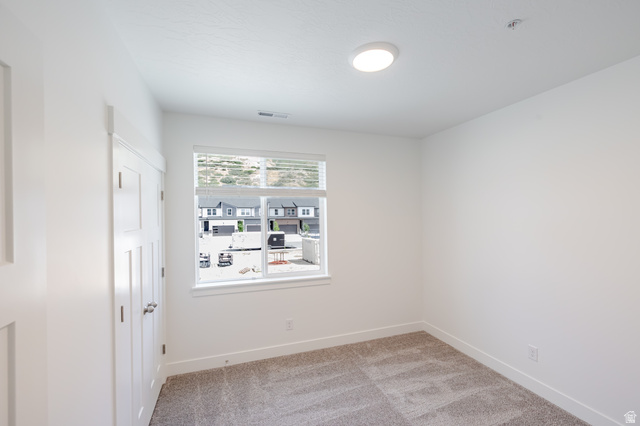 Neutral wall paint, plush carpet flooring, recessed lighting, and a multi-pane window with blinds