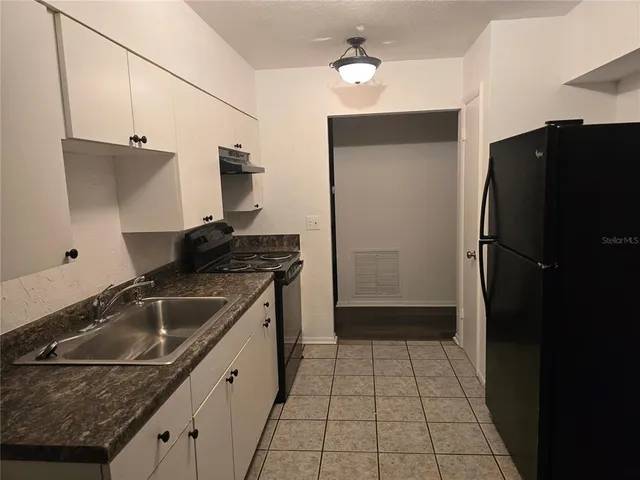 a kitchen with a sink a refrigerator and cabinets
