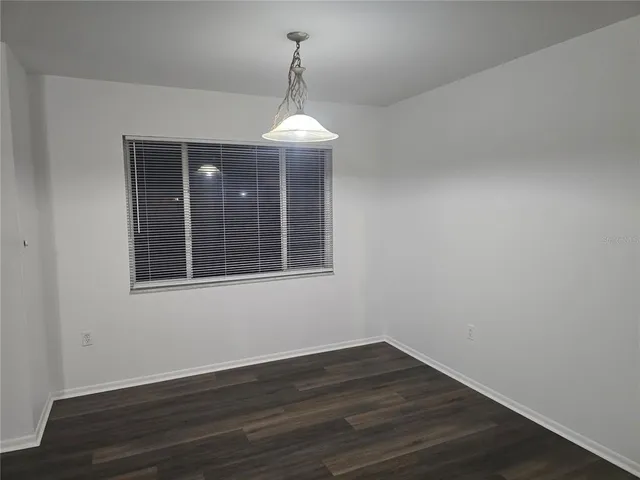 a view of empty room with wooden floor and chandelier
