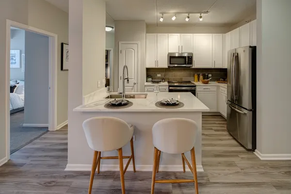 a kitchen with stainless steel appliances granite countertop a refrigerator a stove top oven and a dining table with wooden floor