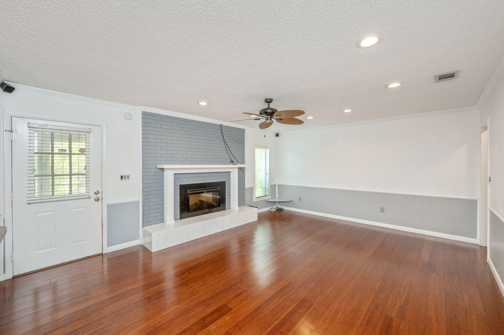 5770 Wildwood Road Crestview, FL 32536 - Photo 7 of 39 an empty room with wooden floor fireplace and windows