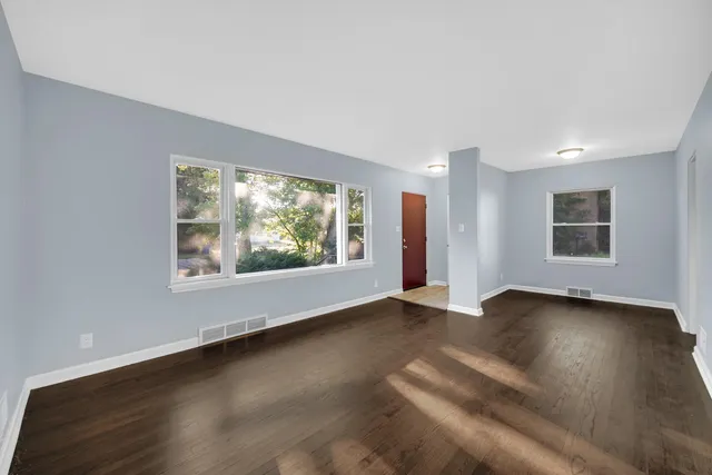 a view of an empty room with a window and wooden floor