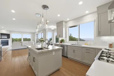 a large kitchen with granite countertop lots of counter top space a sink appliances and cabinets