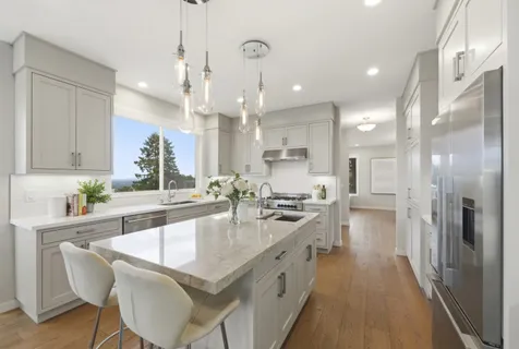 a large white kitchen with refrigerator a sink and a large window
