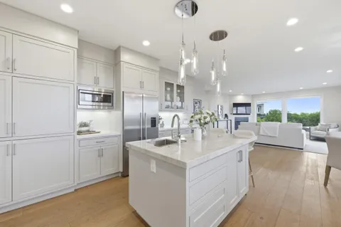 a large white kitchen with a large window and stainless steel appliances
