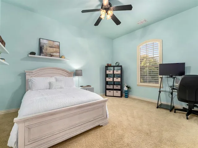 a bedroom with a bed a computer on the desk and chair