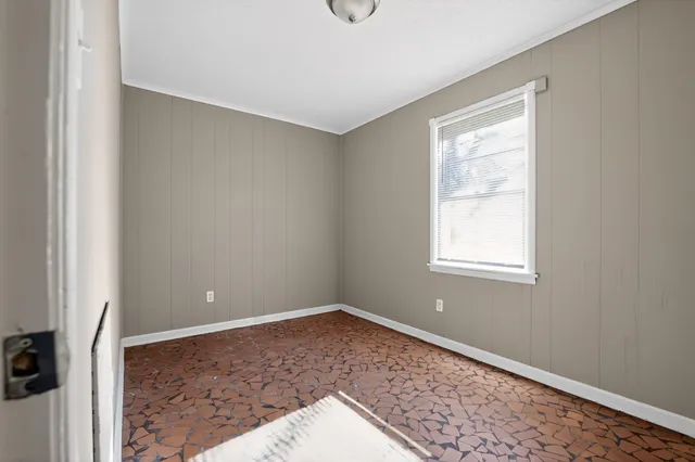a view of an empty room with window and closet area