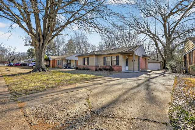 a front view of a house with a yard and large trees