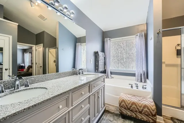 a bathroom with a granite countertop tub sink and mirror