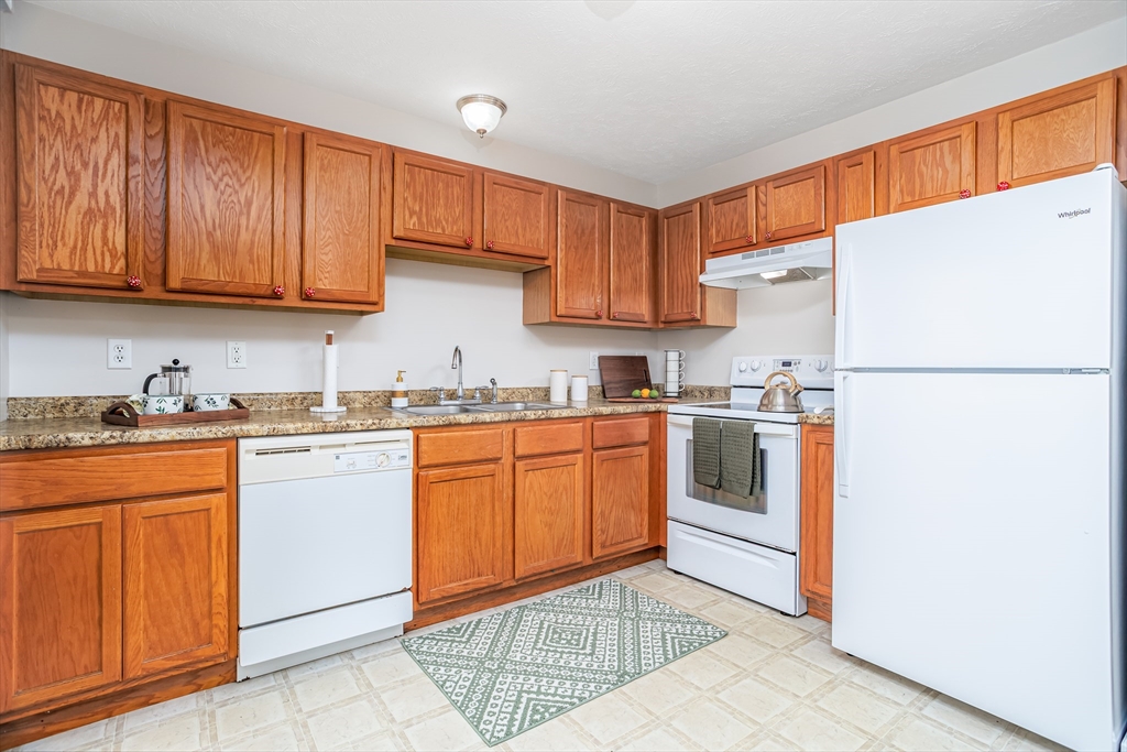 104 Lake Street, Unit 104 Gardner, MA 01440 - Photo 10 of 30 a kitchen with granite countertop a refrigerator sink and cabinets