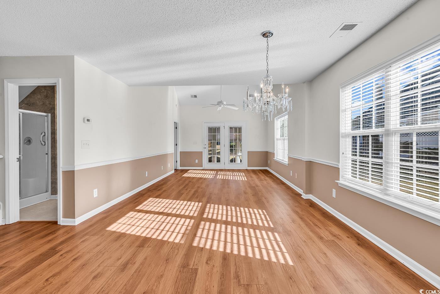 996 Williston Loop, Unit 996 Murrells Inlet, SC 29576 - Photo 5 of 40 Unfurnished dining area with french doors, light wood-type flooring, a chandelier, a textured ceiling, and a ceiling fan