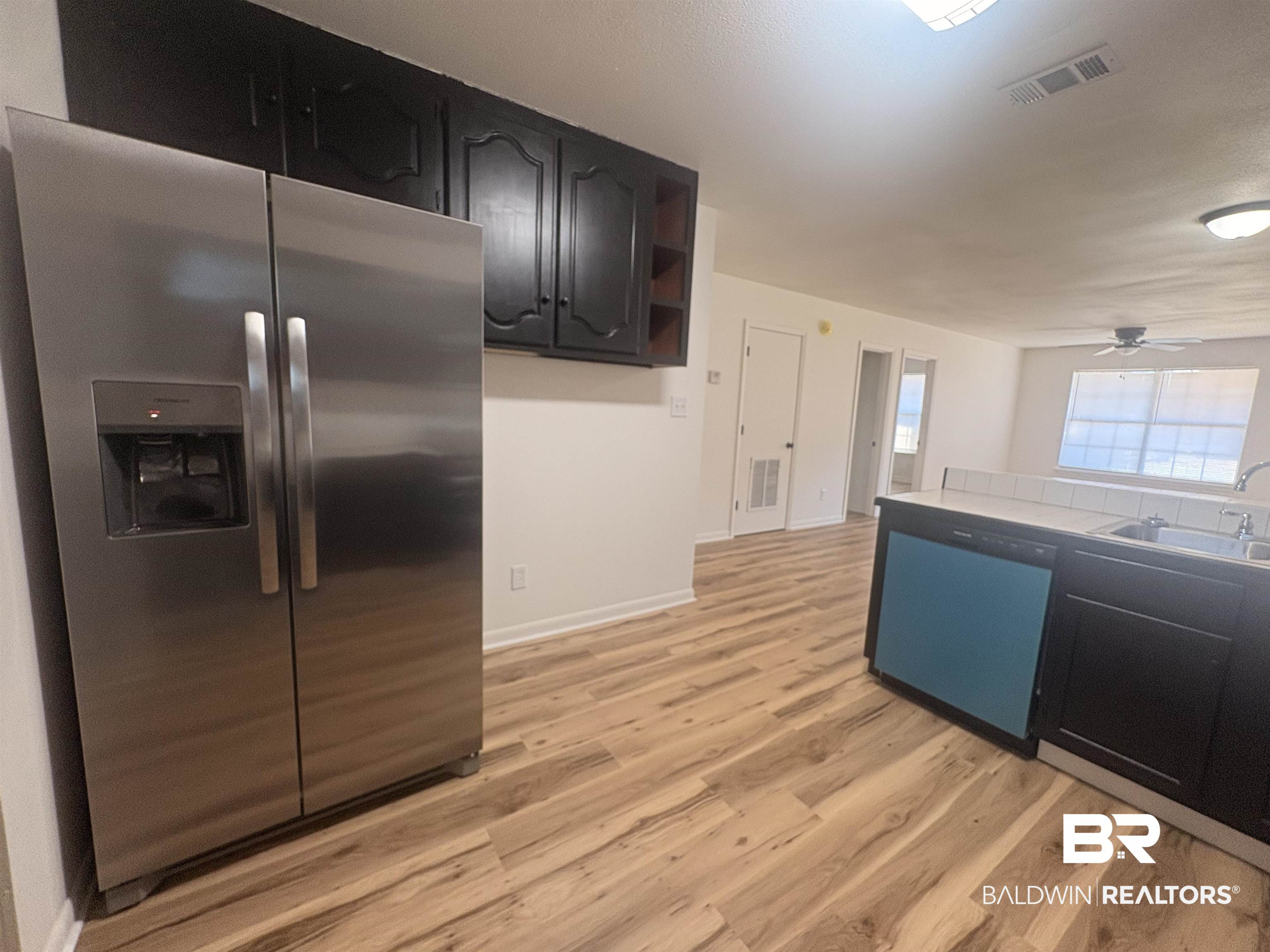 109-111 North Beech Street, Unit A & B Foley, AL 36535 - Photo 6 of 16 Kitchen featuring stainless steel fridge with ice dispenser, dark cabinetry, light wood finished floors, open shelves, and dishwasher