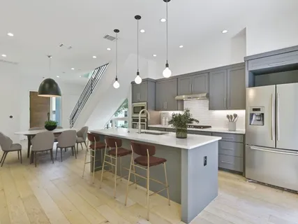 a kitchen with stainless steel appliances granite countertop a sink a stove a refrigerator and island with wooden floor