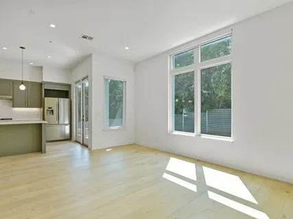 a view of an empty room with a window and a kitchen