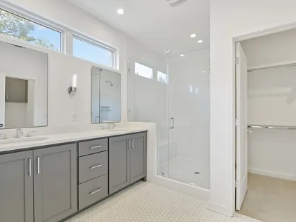 a spacious bathroom with a shower a sink and a mirror