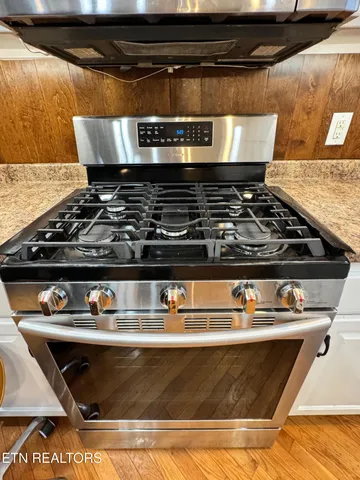 a kitchen with granite countertop a sink a stove and refrigerator