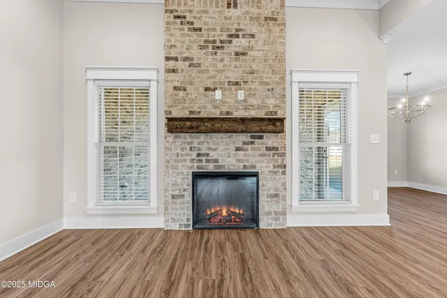 an empty room with a chandelier fan and windows