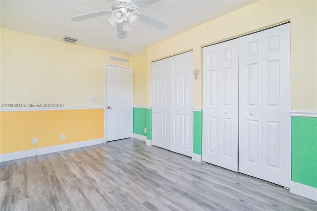 a view of empty room with wooden floor and fan