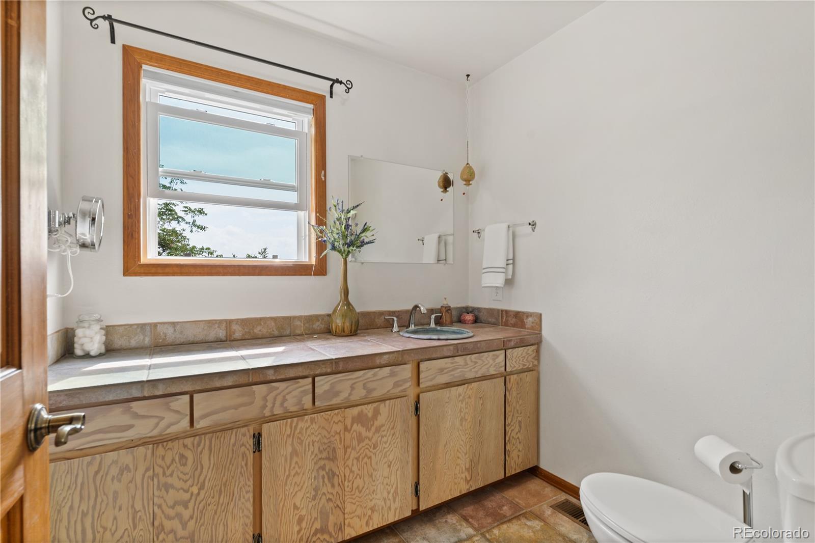 64 Highland Road Palmer Lake, CO 80133 - Photo 10 of 17 a bathroom with a granite countertop sink toilet and mirror