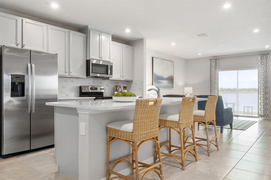 1186 Turtle Is Road Fruitland Park, FL 34731 - Photo 7 of 11 a kitchen with stainless steel appliances granite countertop a refrigerator a stove a sink a dining table and chairs