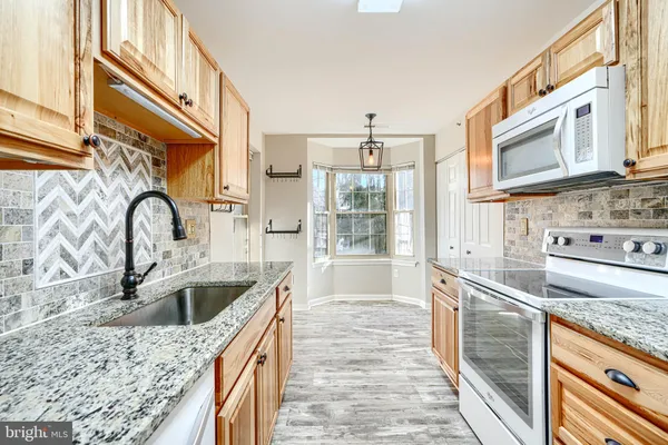 a kitchen with granite countertop a sink and a stove top oven