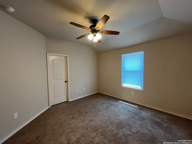 a view of an empty room with a ceiling fan and window