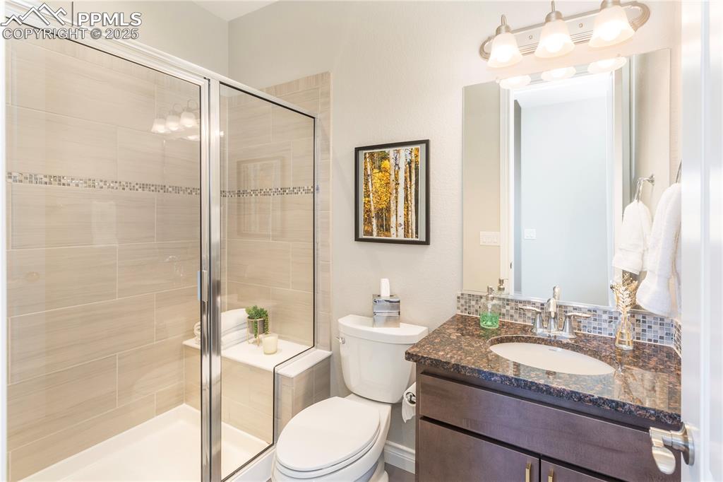 12516 Stone Valley Drive Peyton, CO 80831 - Photo 29 of 44 a bathroom with a granite countertop sink toilet mirror and shower