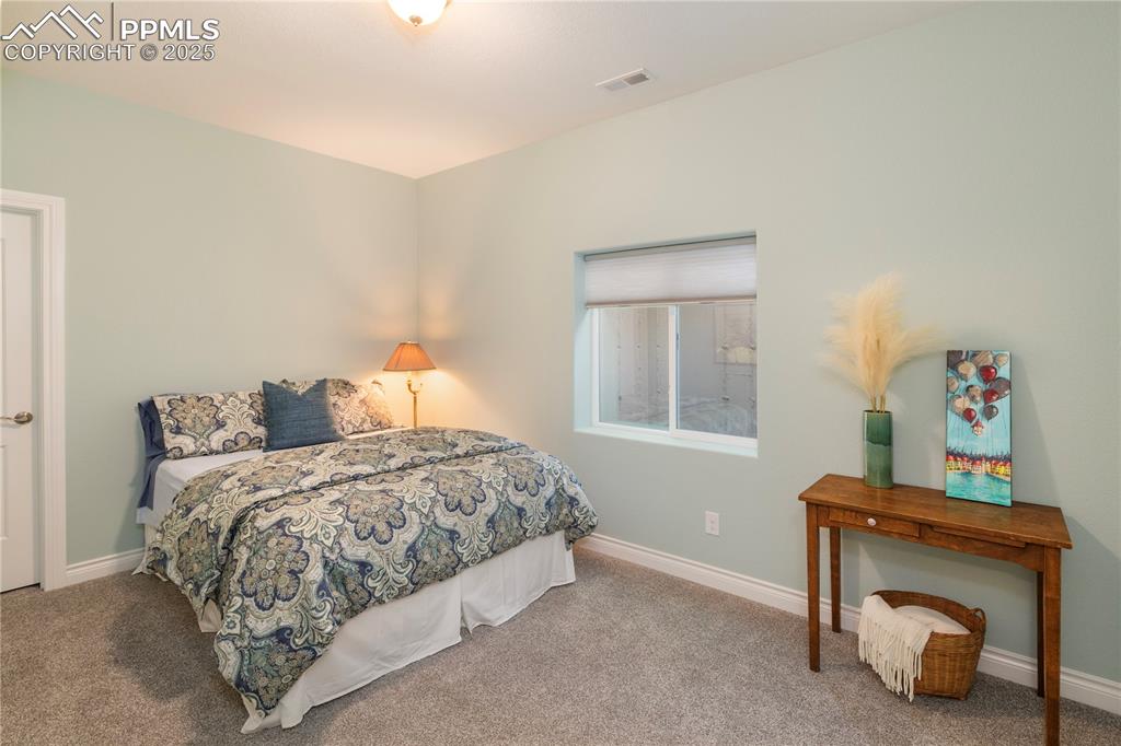 12516 Stone Valley Drive Peyton, CO 80831 - Photo 35 of 44 a bedroom with a bed and a lamp on table
