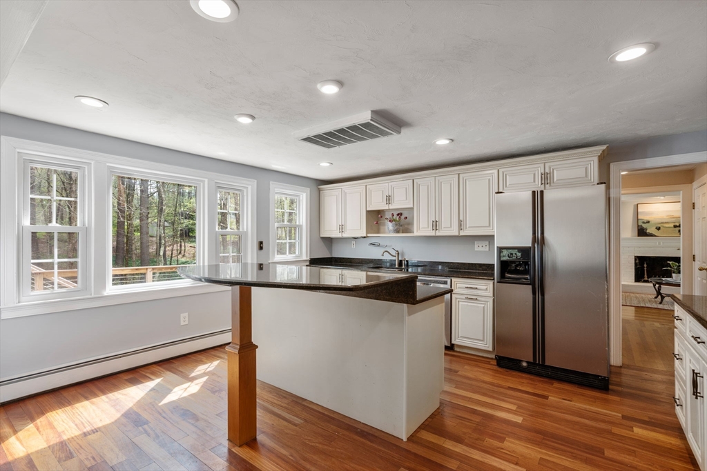 27 Middle Road Sudbury, MA 01776 - Photo 9 of 33 a kitchen with stainless steel appliances granite countertop a refrigerator a sink a stove and white cabinets with wooden floor next to windows