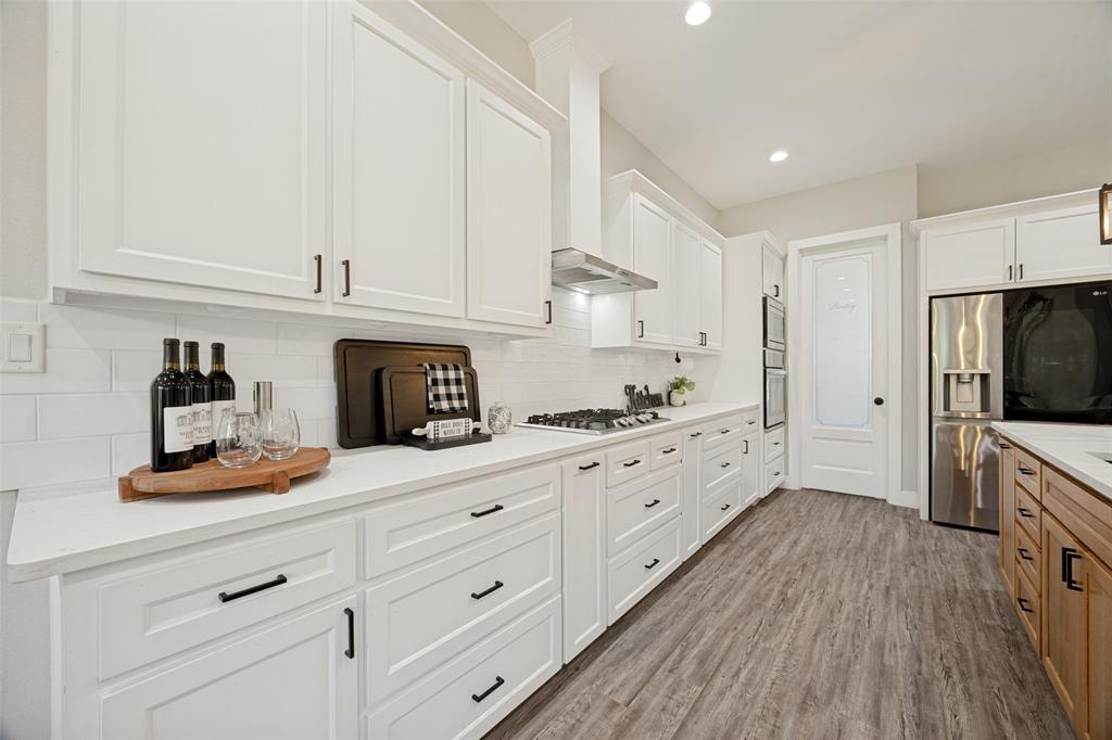1105 Ranch Drive Bonham, TX 75418 - Photo 4 of 25 Modern kitchen featuring white cabinetry, light-toned countertops, and wood-finish flooring, large walk in pantry, electric oven and microwave