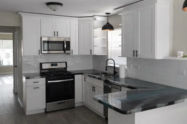 a kitchen with stainless steel appliances granite countertop white cabinets a stove top oven a sink and dishwasher