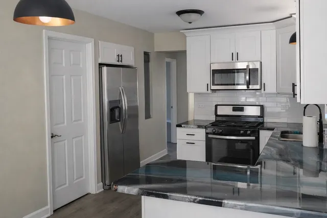 a kitchen with stainless steel appliances granite countertop a stove a refrigerator and a microwave