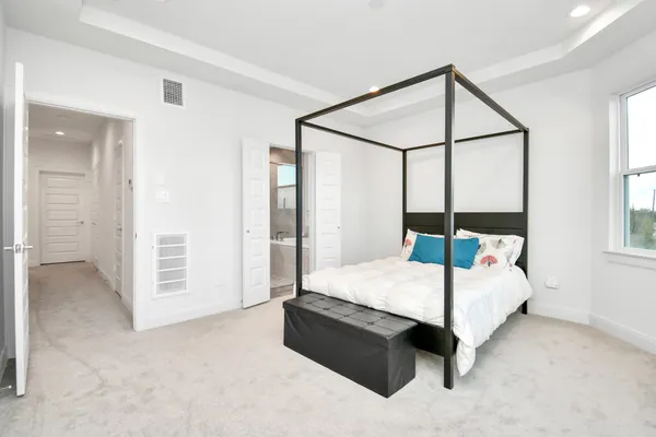 a bedroom with a bed table and two window