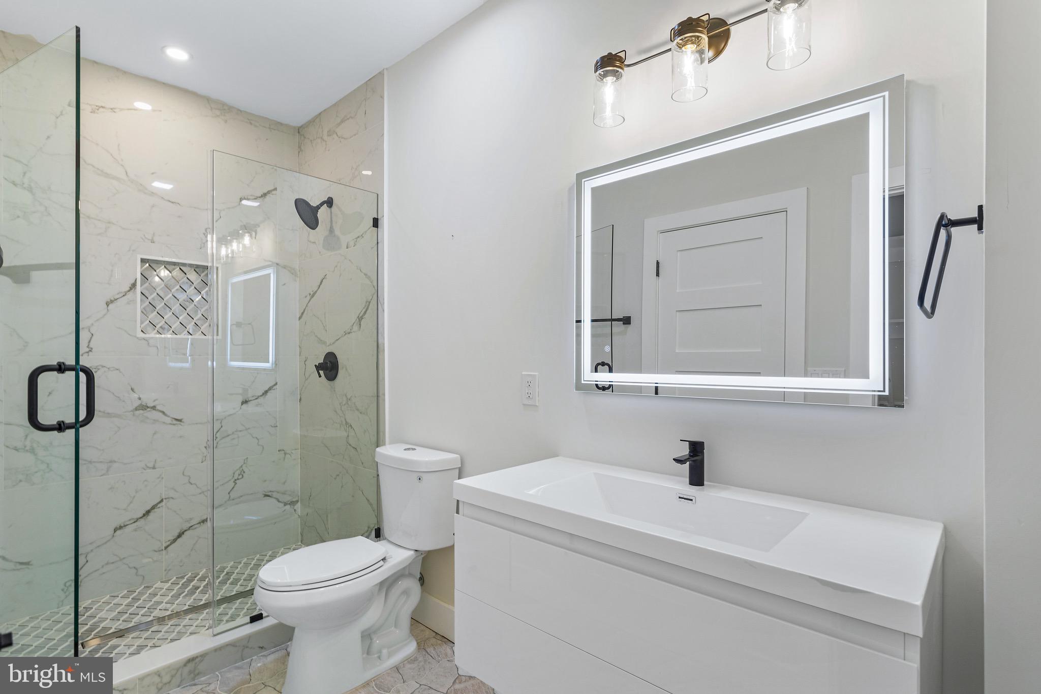 1118 Neal Street Northeast, Unit 2 Washington, DC 20002 - Photo 11 of 25 a bathroom with a toilet sink a mirror and shower