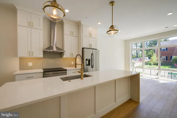 a large kitchen with stainless steel appliances a refrigerator and a stove top oven