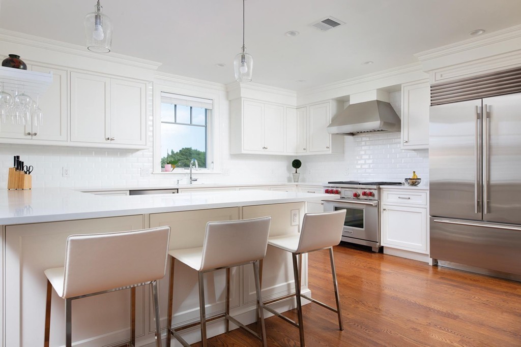 27 Summit Avenue, Unit 27 Brookline, MA 02446 - Photo 5 of 21 a kitchen with stainless steel appliances a sink a stove a refrigerator and white cabinets with wooden floor
