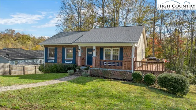 a view of a brick house with a yard plants and large tree