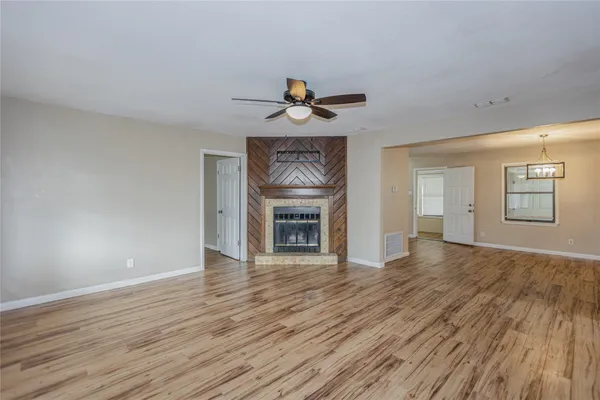 a view of an empty room with window and wooden floor