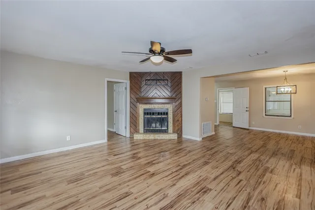 a view of an empty room with window and wooden floor