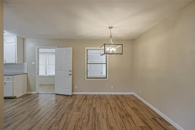 a view of empty room with wooden floor and window