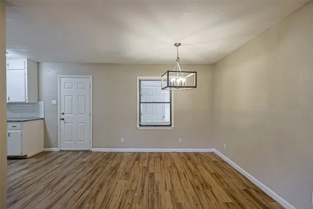 a view of empty room with wooden floor and window