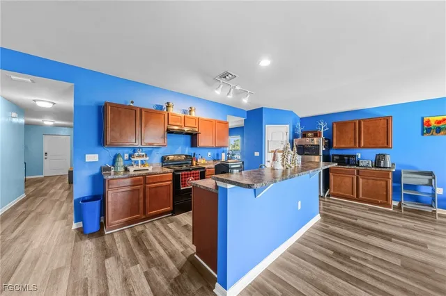 a kitchen with stainless steel appliances kitchen island granite countertop a stove top oven a sink dishwasher a dining table and chairs with wooden floor